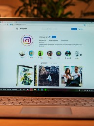 A computer on the table showing an Instagram profile